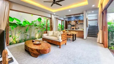 a living room with a coffee table and a kitchen at Casa De Gracia Sanur Beach by Nagisa Bali in Sanur