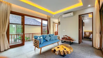 a living room with a blue couch and a balcony at Casa De Gracia Sanur Beach by Nagisa Bali in Sanur