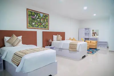 a bedroom with two beds and a couch in it at The Pandan Sari Hotel in Jimbaran