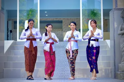 a group of four women praying in front of a wall at The Pandan Sari Hotel in Jimbaran