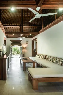 a room with two beds and a ceiling fan at Segara Beach House Villa - Kuta in Kuta