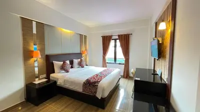 a bedroom with a bed and a desk and a television at The Tandibayang Hotel & Villas in Legian