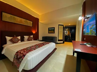 a hotel room with a large bed and a desk at The Tandibayang Hotel & Villas in Legian