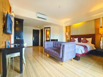a hotel room with a bed and a couch and a desk at The Tandibayang Hotel & Villas in Legian