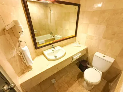 a bathroom with a sink and a toilet and a mirror at The Tandibayang Hotel & Villas in Legian
