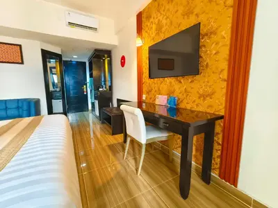 a bedroom with a desk with a television on a wall at The Tandibayang Hotel & Villas in Legian