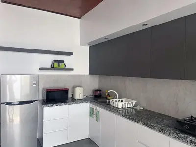 a kitchen with white cabinets and a stainless steel refrigerator at Eimas Hive in Kerobokan