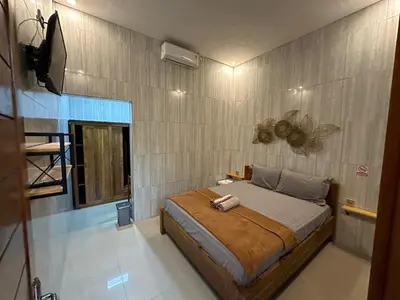 a bedroom with a bed and a tv on a wall at Kubu Alvian Guest House in Seminyak
