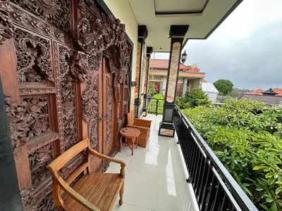 a balcony with wooden benches on a building at Kubu Alvian Guest House in Seminyak