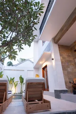 a patio with two chairs and a tree at Villa Dimaz in Seminyak