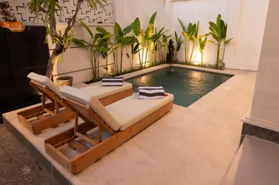 a swimming pool with a chaise lounge in a room with a swimming pool at Villa Dimaz in Seminyak