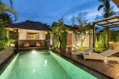 a swimming pool with a villa in the background at Luxurious and Cozy King Beds, Pool, closed living room in Kuta