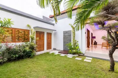 a white house with a palm tree in the yard at Seminyak lush tropical paradise close to Eatstreet in Seminyak