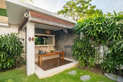 a patio with a wooden table under a roof at Villa private Pool in Seminyak, Car Park fast WIFI in Kuta