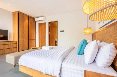 a bedroom with a white bed and a television at Casa Tropicale Seminyak in Seminyak