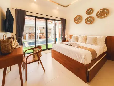 a bedroom with a bed and a desk and a window at Villa Zanetta By Bali Asia Villa in Kerobokan