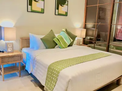 a bedroom with a large white bed with green pillows at Putu Soemantri Four Persons Villas in Denpasar