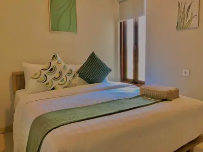 a large bed in a room with a window at Putu Soemantri Four Persons Villas in Denpasar