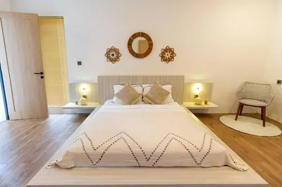 a bedroom with a large white bed and a chair at Chic modern villa, 5 minute walk to Legian beach in Legian