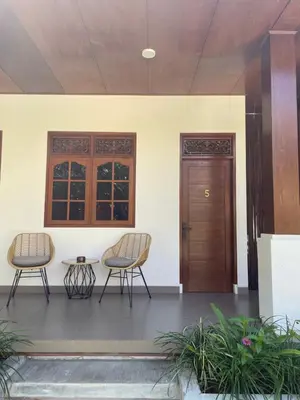 two chairs and a table in front of a door at Kaman Bali Guesthouse in Seminyak