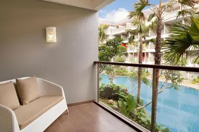 a room with a balcony with a view of a swimming pool at Ramada Encore by Wyndham Seminyak Bali in Seminyak