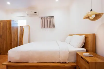 a bedroom with a white bed and a wooden table at Villa Isla Bali in Seminyak