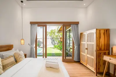 a bedroom with a bed and a door to a yard at Ami villa in the heart of Canggu in Canggu