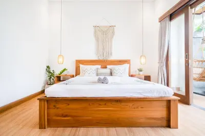 a bedroom with a wooden bed with white sheets at Ami villa in the heart of Canggu in Canggu