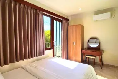 a bedroom with a bed and a desk and a window at Narendra 1 BR Apartment in Jimbaran