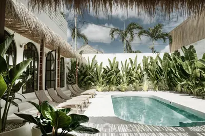 a swimming pool in a resort with chairs and trees at Villa Almaz Seminyak in Seminyak