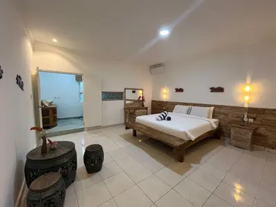 a large bedroom with a bed and a bathroom at Lavender star house in Kuta