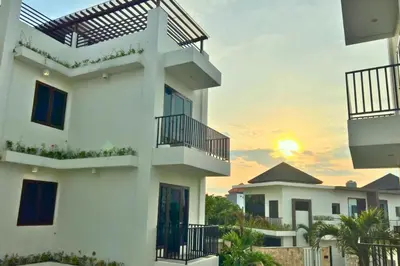 a white building with a sunset in the background at Adaline 2 BR Apartment in Jimbaran