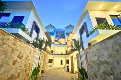 a large white building with palm trees in front of it at Adaline 2 BR Apartment in Jimbaran