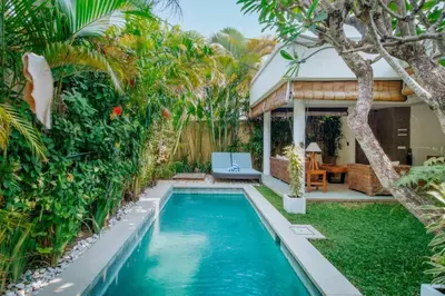 a swimming pool in the backyard of a house with palm trees at Cozy & Private 1 Bed Pool Villa in Trendy Umalas in Kerobokan