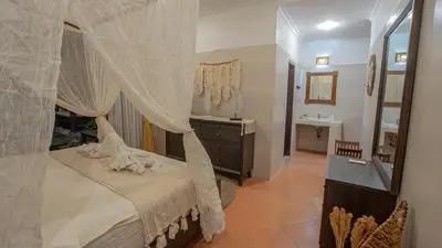 a bedroom with a canopy bed with a dresser and a mirror at Leluhur 2 - 3BR, Free Nmax, Airport Pick Up and YT Premium in Seminyak
