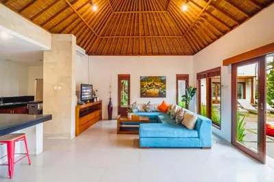 a living room with a blue couch and a kitchen at Minara 4 BR Private Pool Villa in Canggu