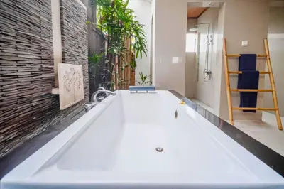 a large white bath tub in a room with a brick wall at Minara 4 BR Private Pool Villa in Canggu
