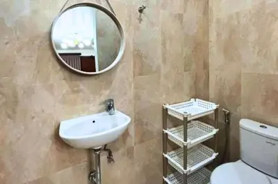 a bathroom with a sink and a mirror and a toilet at Reline 1 BR Studio with Sofa Bed in Jimbaran