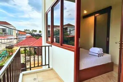 a balcony with a room with a bed and windows at Anyaa 3 BR Apartment in Jimbaran