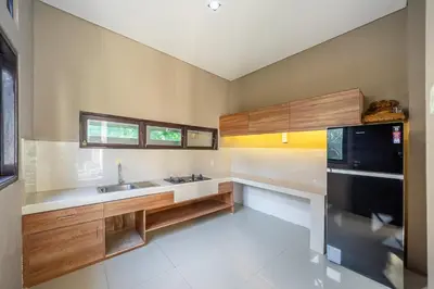 a kitchen with a sink and a black refrigerator at Aradhia Villa Nusa Dua in Nusa Dua