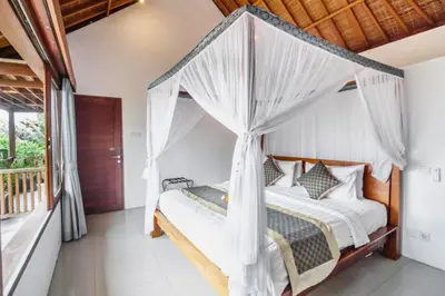 a bedroom with a canopy bed with mosquito nets at Camana 1 BR Villa With Shared Pool in Canggu