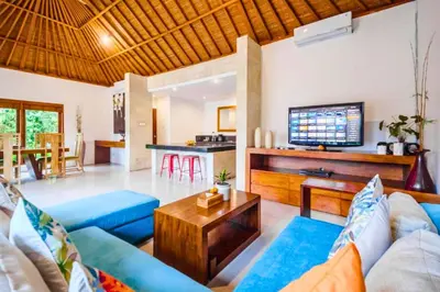 a living room with a blue couch and a table at Camana 1 BR Villa With Shared Pool in Canggu