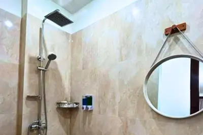 a bathroom with a shower with a round mirror at Willy 4 BR Comfort Quadruple Room in Jimbaran