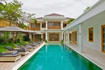 a villa with a swimming pool and lounge chairs at Narasnama 6 BR Private Pool Villa in Canggu