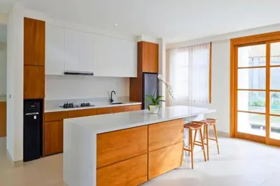 a kitchen with a white counter and wooden cabinets at Narasnama 6 BR Private Pool Villa in Canggu