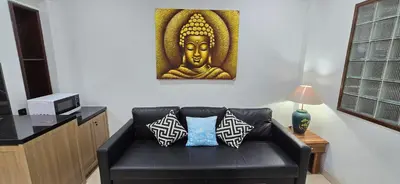a living room with a black leather couch with a picture of a budgie at C&C Jayakarta Residence Apartment Legian Kuta Bali in Seminyak