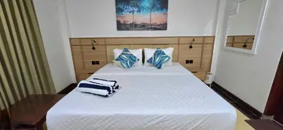 a bedroom with a large white bed with blue pillows at C&C Jayakarta Residence Apartment Legian Kuta Bali in Seminyak