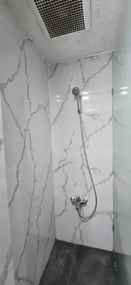 a bathroom with white marble walls and a shower at C&C Jayakarta Residence Apartment Legian Kuta Bali in Seminyak