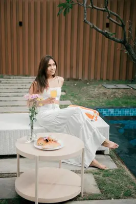 a woman sitting on a bench with a glass of juice at Seminyak Villa Luxury 4BR near Beach Lafavela in Seminyak