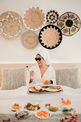 a woman sitting on a bed with a tray of food at Seminyak Villa Luxury 4BR near Beach Lafavela in Seminyak